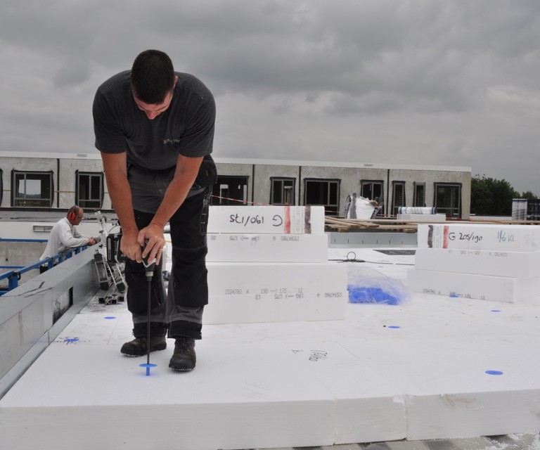 Projectfoto van een verwerker die een SuperTop dakisolatieplaat bevestigd op het plat dak. 