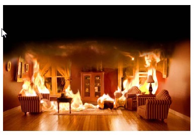 De binnenzijde van een woning waarbij een brand woedt en er zwarte rook hangt.