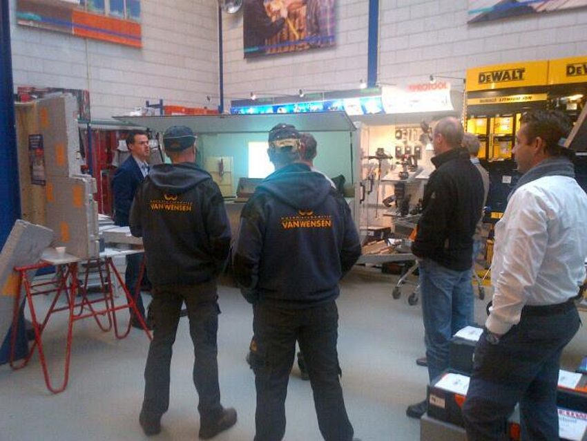 Foto van een groep cursisten die tijdens een training van BEWI IsoBouw luisteren naar de uitleg.