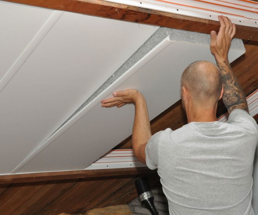 Projectfoto van een SlimFix Deco isolatieplaat die op het randprofiel wordt geplaatst door een man. 