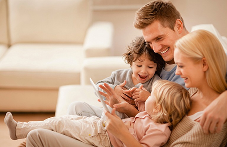 Foto van een gezin met jonge kinderen die warm en knus bij elkaar zitten. 