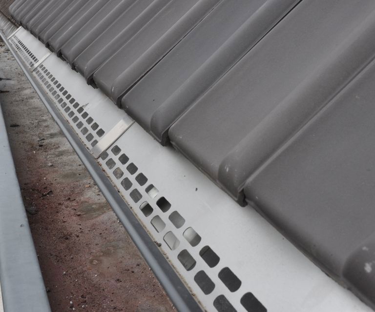 Close-up van een SlimFix RenoGoot, in de bestaande dakgoot en met dakpannen. 