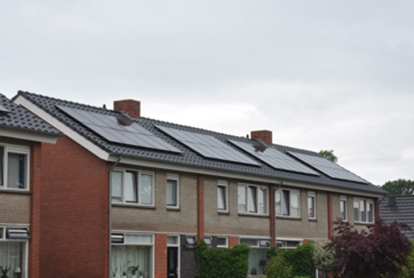Projectfoto van een rij woningen waar de renovatiewerkzaamheden hebben plaatsgevonden. Er liggen al dakpannen en zonnepanelen.  