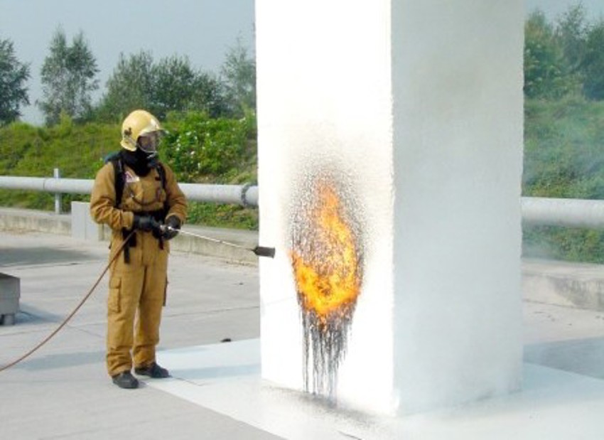 Foto van een brandweerman die een brandtest doet bij een witte EPS blok. 