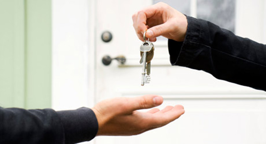 Foto van twee armen waarbij de ene persoon een sleutel van een woning overhandigd aan de ander. 