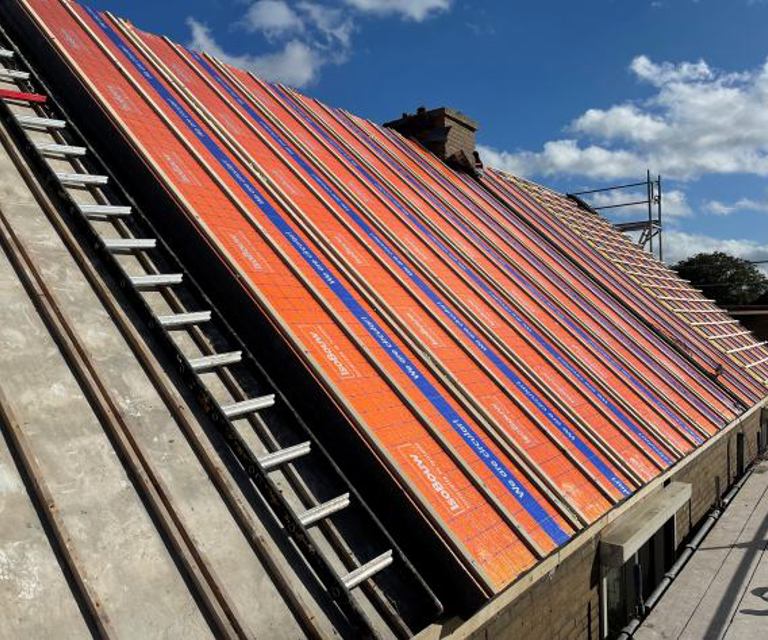 Projectfoto van een dak waarbij een gedeelte oud dakbeschot heeft en de andere helft al SlimFix RenoTwin na-isolatie. 