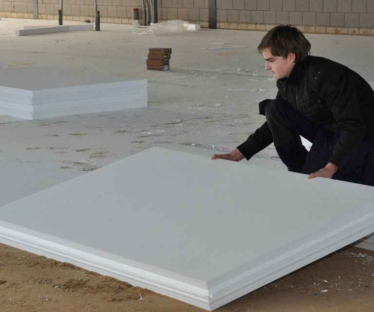 Projectfoto van een verwerker die een Klik-vloerplaat legt in een hal waar klik-vloerplaten liggen.