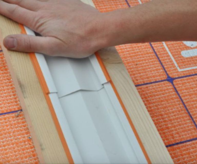 Close-up van een hand die een Reno profiel bevestigd tussen renovatieplaten. 