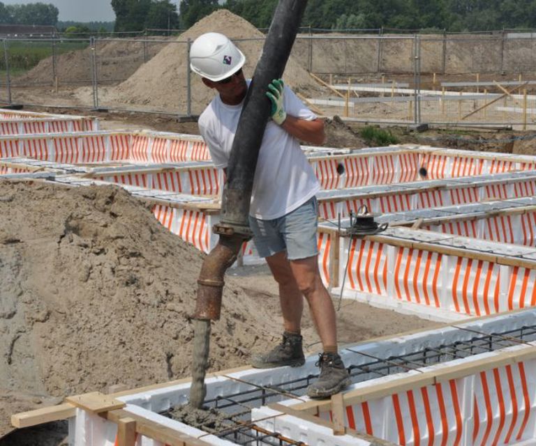 Projectfoto van een verwerker die beton stort in de wapening van een PowerKist funderingsbekisting. 