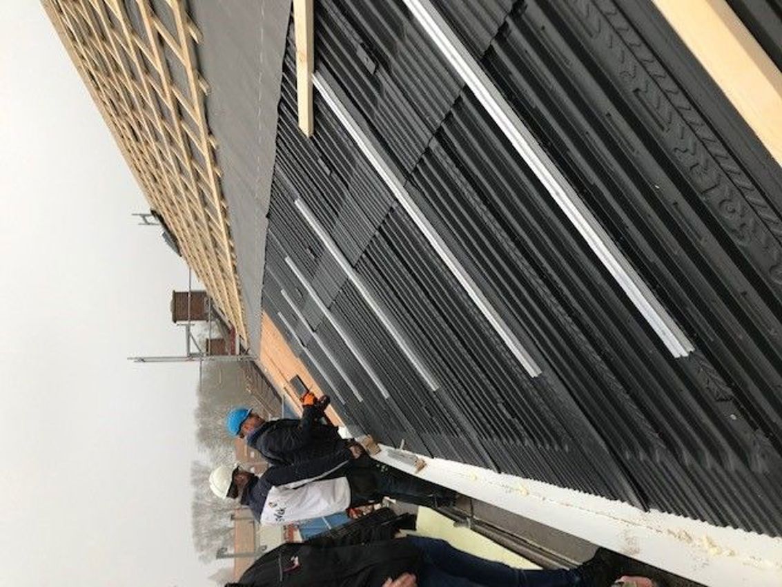 Projectfoto op de bouw waar dakdekkers een rij aan modules monteren. 