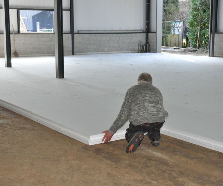 Projectfoto van een verwerker die een vloer met Eco Klik-vloerplaten legt in een fabriekshal. 