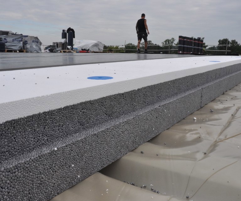 Close-up van PowerTop Protect isolatieplaten die op een bouwplaats worden gelegd op het plat dak. 