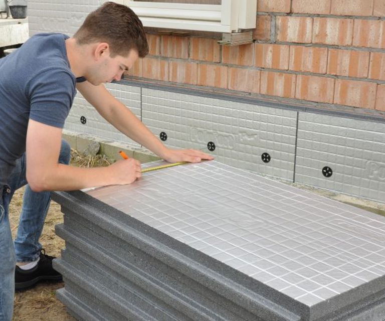 Projectfoto van een verwerker die een PolyFort Pro spouwmuurisolatieplaat aftekent op maat.