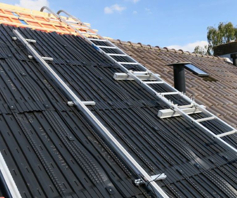 Close-up van een dak met daar op diverse solarmodules en een nokladder.