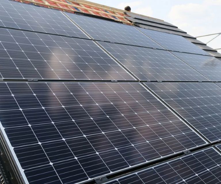 Close-up van diverse zonnepanelen die op de SlimFix Xt Solar daksysteem liggen. 
