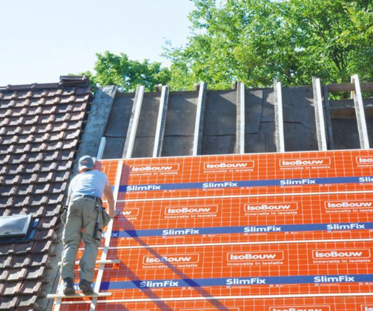 Projectfoto van een dakdekker die op een dak met SlimFix Spoor isolatieplaten staat. 