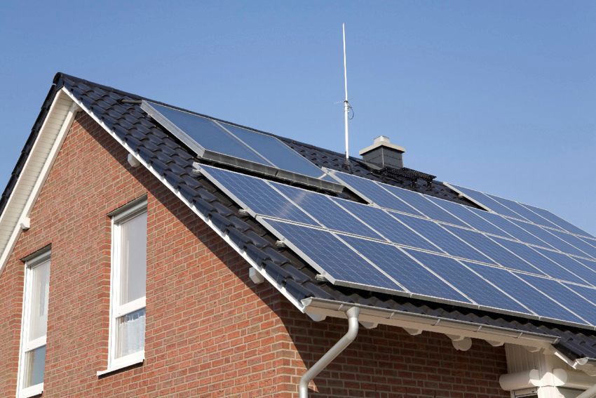Foto van een vrijstaande woning met zonnepanelen op het hellende dak. 