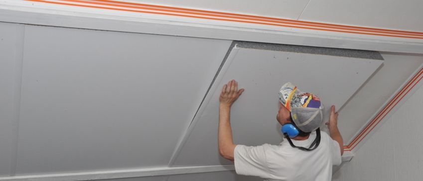 Projectfoto van een man die SlimFix Deco zolderisolatie plaatst tussen de gordingen. 