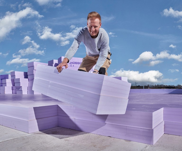 Projectfoto van een verwerker die een meerlaagse XPS EVO isolatieplaat plaatst op een plat dak. 