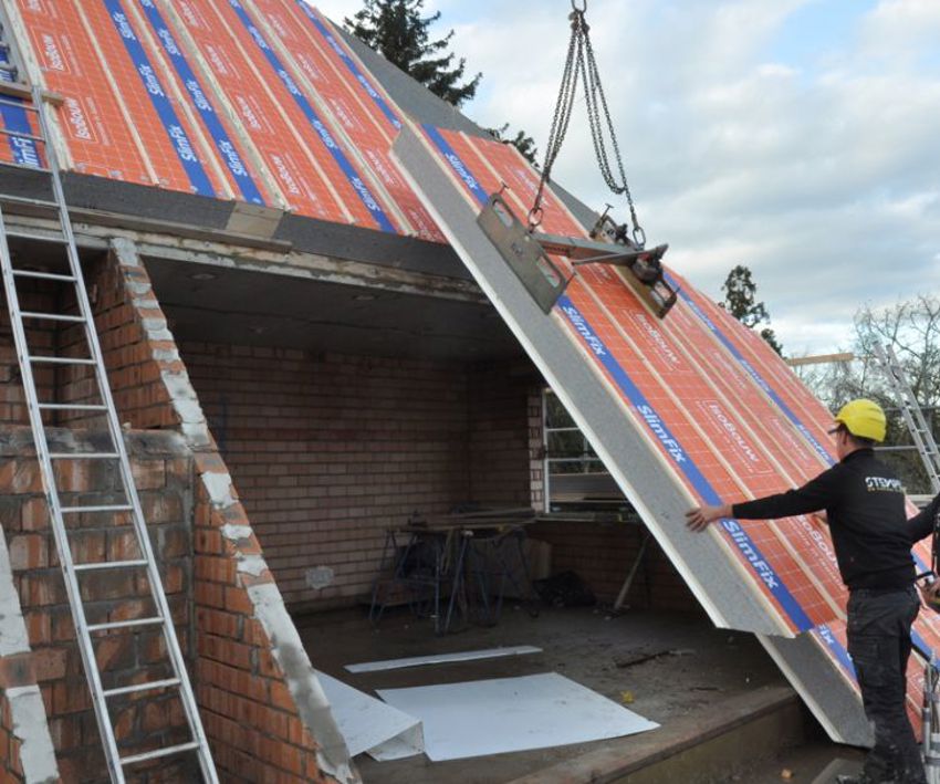 Projectfoto van een dakdekker die een SlimFix XT Passief dakpaneel plaatst m.b.v. een hijsklem.