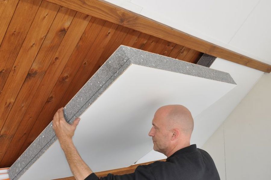 Projectfoto van een man die een SlimFix Deco isolatieplaat plaatst aan de binnenzijde op de gording.