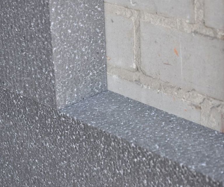 Close-up van de PolyStuc buitengevelisolatieplaat tegen de buitenmuur. 