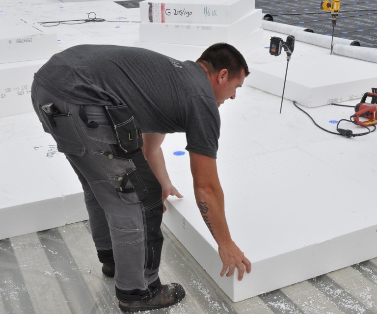 Projectfoto van een verwerker die een SuperTop dakisolatieplaat op het plat dak legt. 