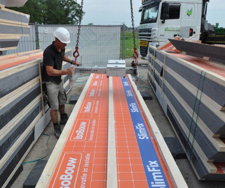 Projectfoto van een persoon die met een hijsklem een SlimFix Passief M plaat ophijst van een stapel.