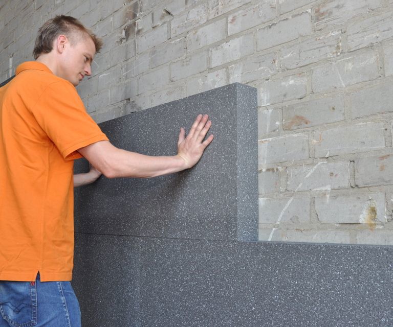 Projectfoto van een verwerker die de PolyStuc buitengevelisolatieplaat plaatst tegen de buitenmuur. 