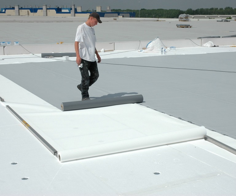 Projectfoto van een verwerker die folie uitrolt over witte isolatieplaten van EPS isolatiemateriaal. 