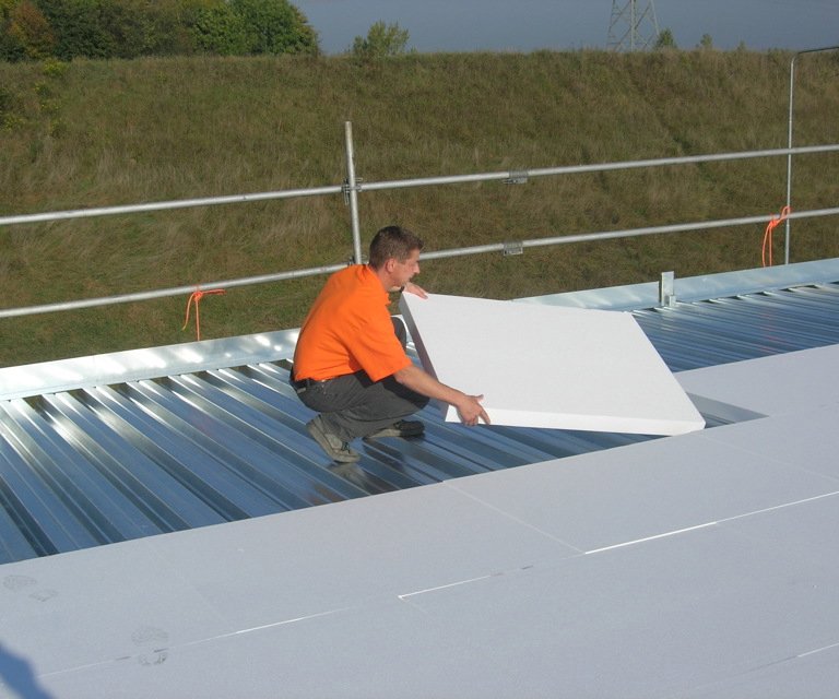 Projectfoto van een verwerker die witte EPS isolatie plaatst op een plat dak. 