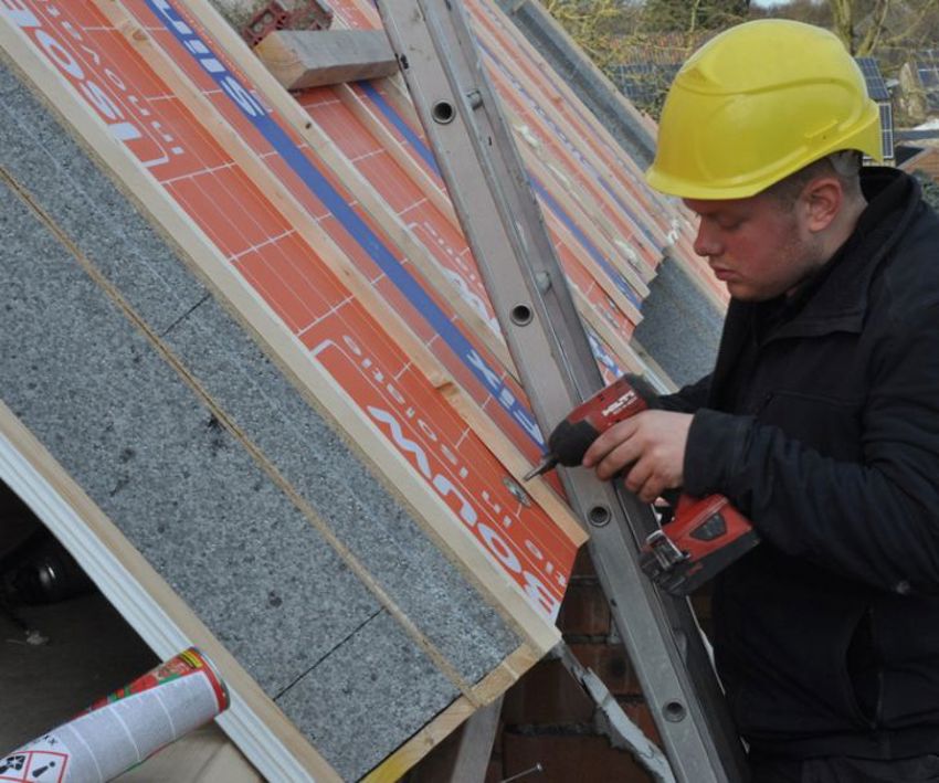 Projectfoto van een dakdekker die een SlimFix XT Passief dakpaneel vastschroeft.