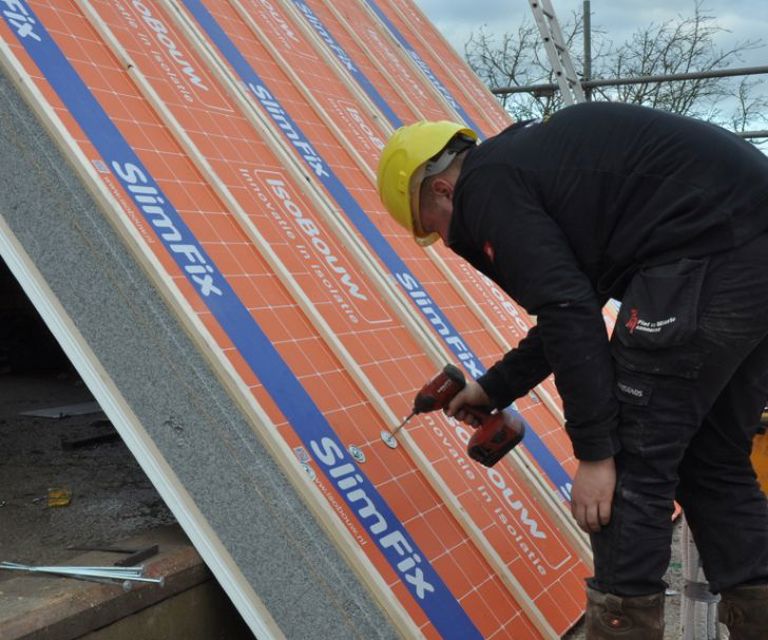 Projectfoto van een dakdekker die een SlimFix XT Passief dakpaneel vastschroeft.