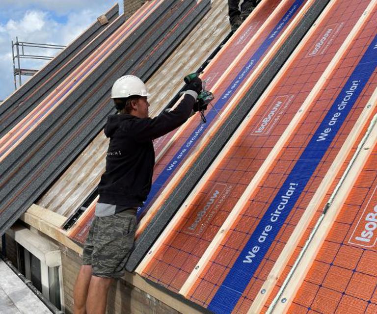 Projectfoto van een dakdekker die SlimFix RenoTwin dakisolatie bevestigd op het dakbeschot. 