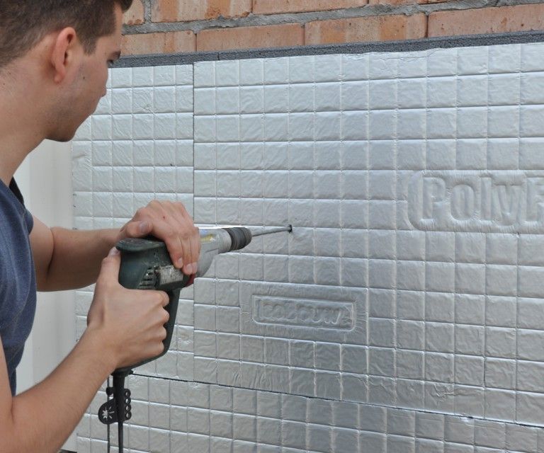 Close-up van het boren in de IsoFort spouwisolatieplaat voor het plaatsen van het anker. 