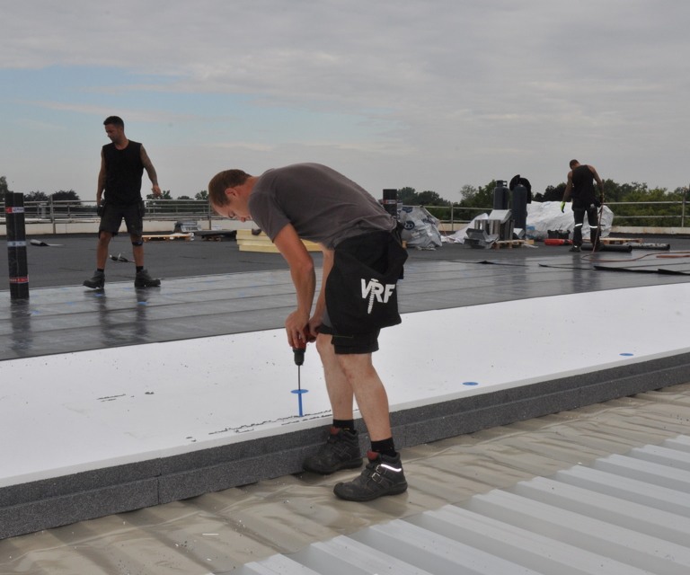 Projectfoto van een verwerker die de PowerTop isolatieplaat van bevestigingsmateriaal voorziet. 