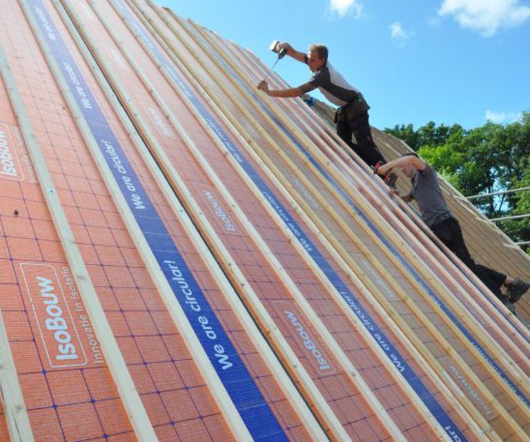 Projectfoto van dakdekkers die SlimFix RenoTwin dakisolatieplaten aan het bevestigen zijn. 